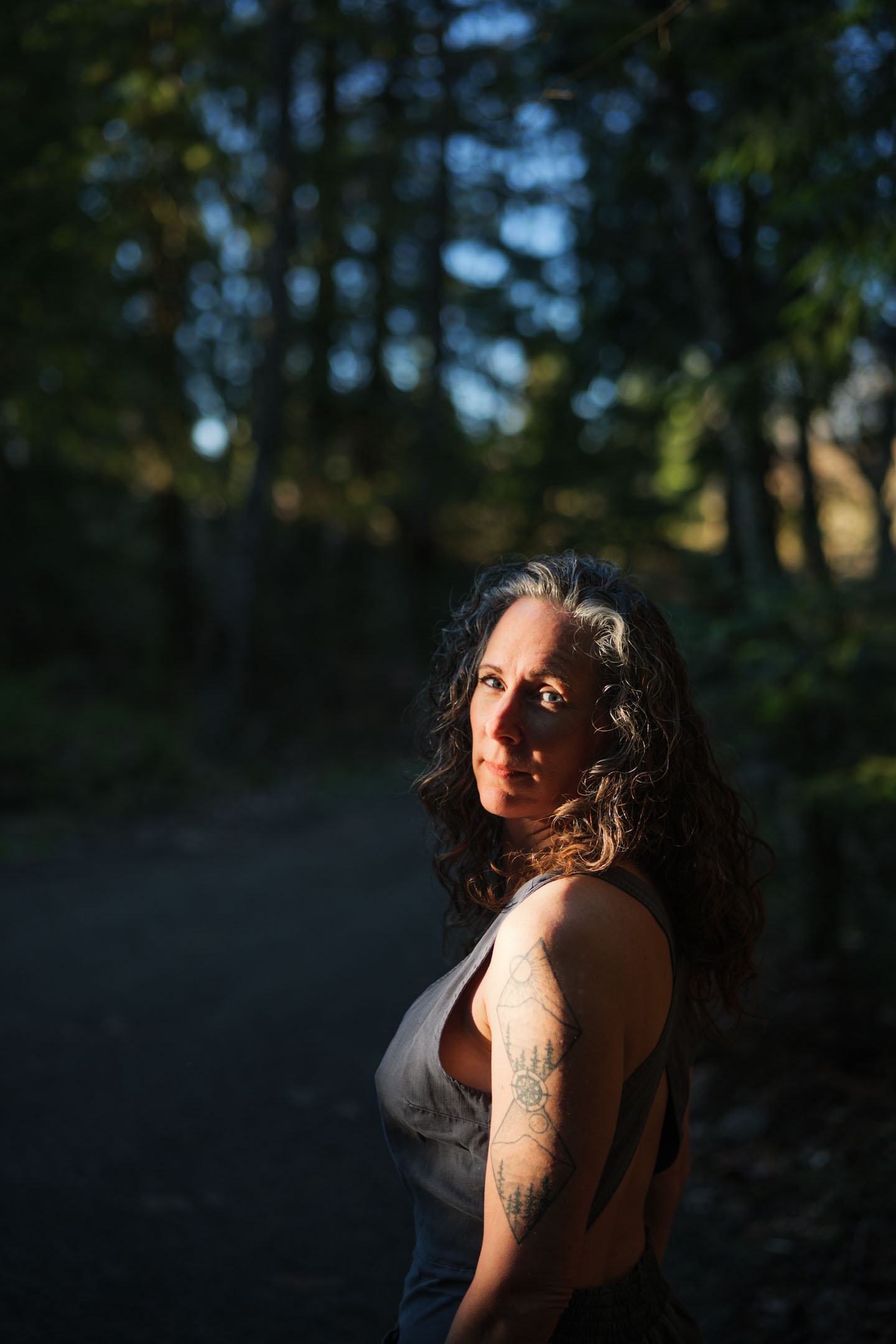 Kate Ensor looking back over her shoulder on a dark forest path